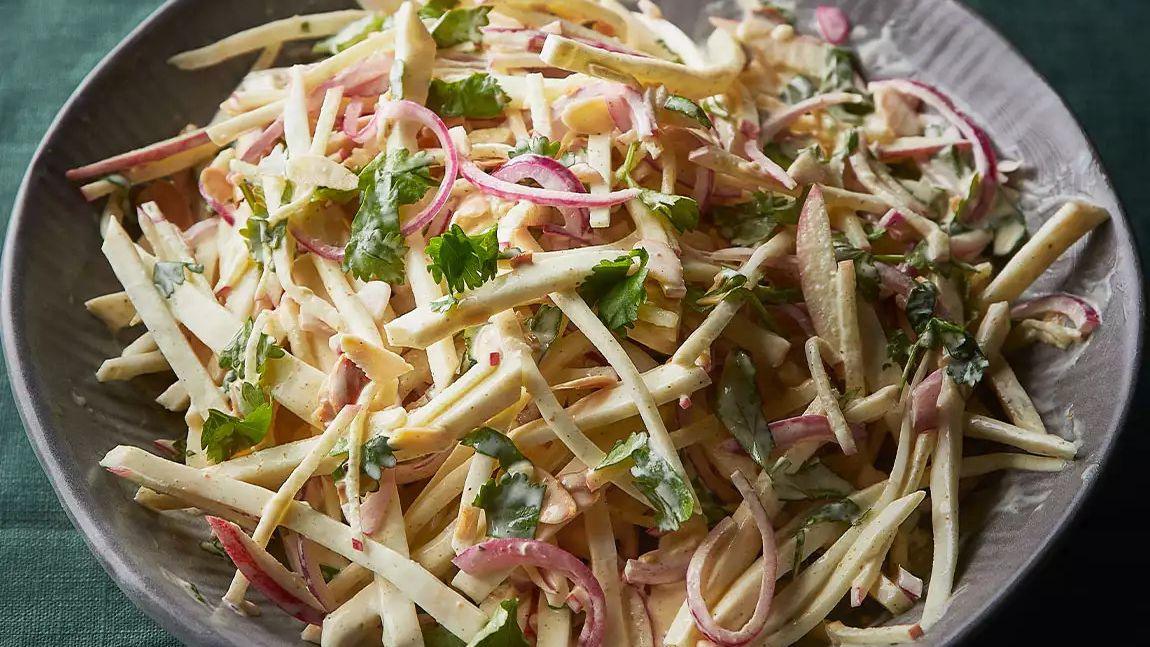 Curried celeriac slaw with red onion, apple, herbs, and creamy dressing in a bowl