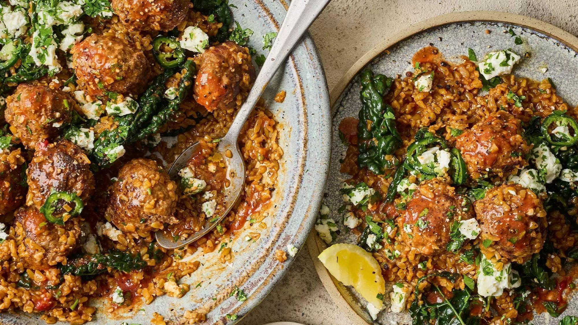 Lamb and onion meatballs with freekeh pilaf, kale, herbs, feta, and lemon on rustic plates