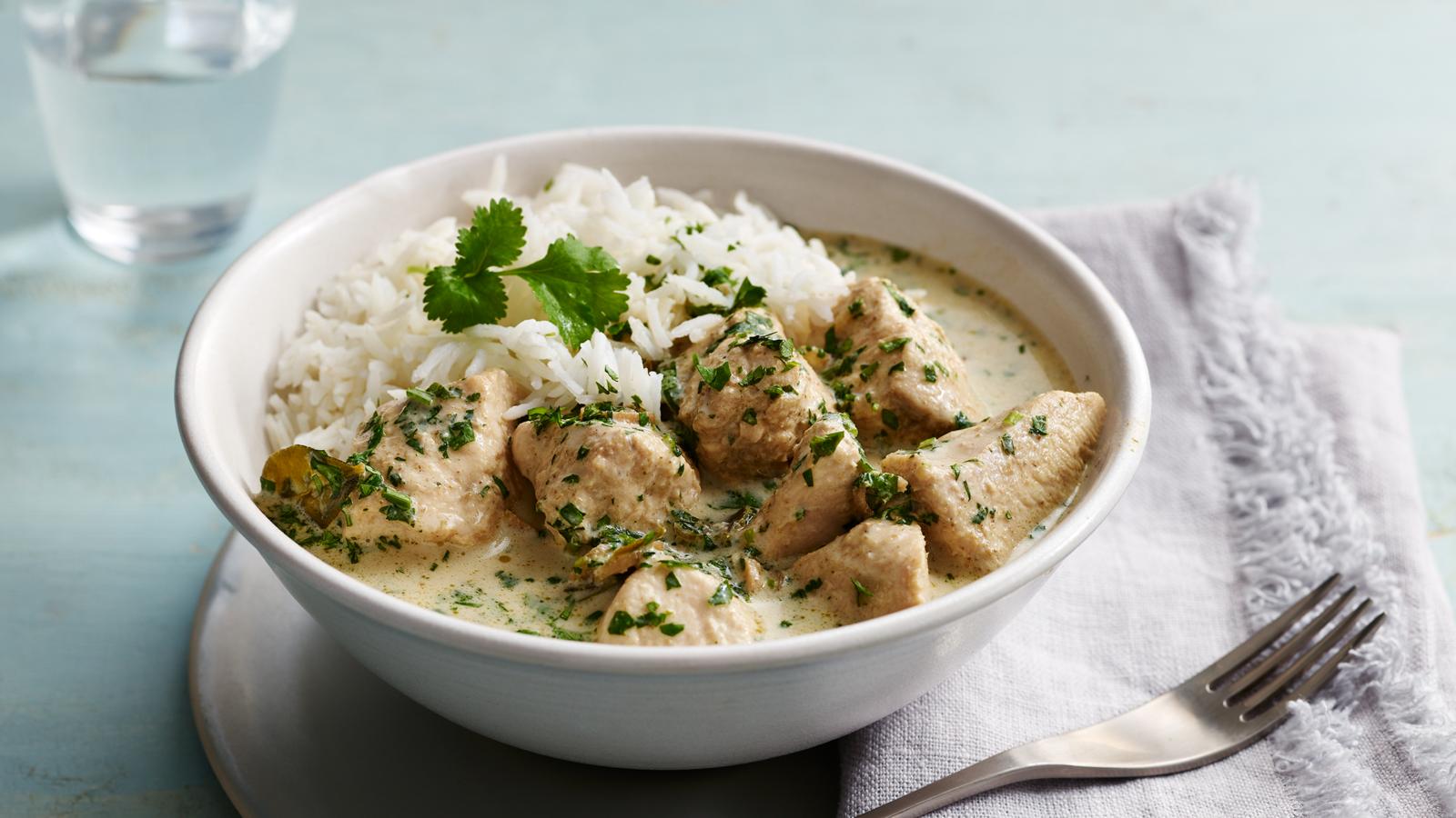Creamy Thai green chicken curry with fresh coriander and lime leaves in a wok, served with jasmine rice.