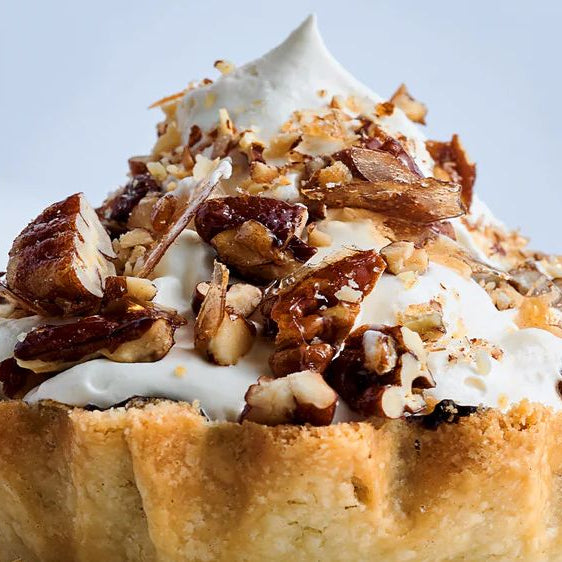 Mont Blanc tart with whipped cream, chopped nuts, and pastry crust on white background
