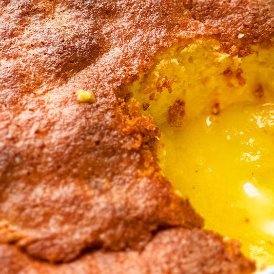 Golden baked lemon pudding with a gooey, creamy lemon center in a baking dish