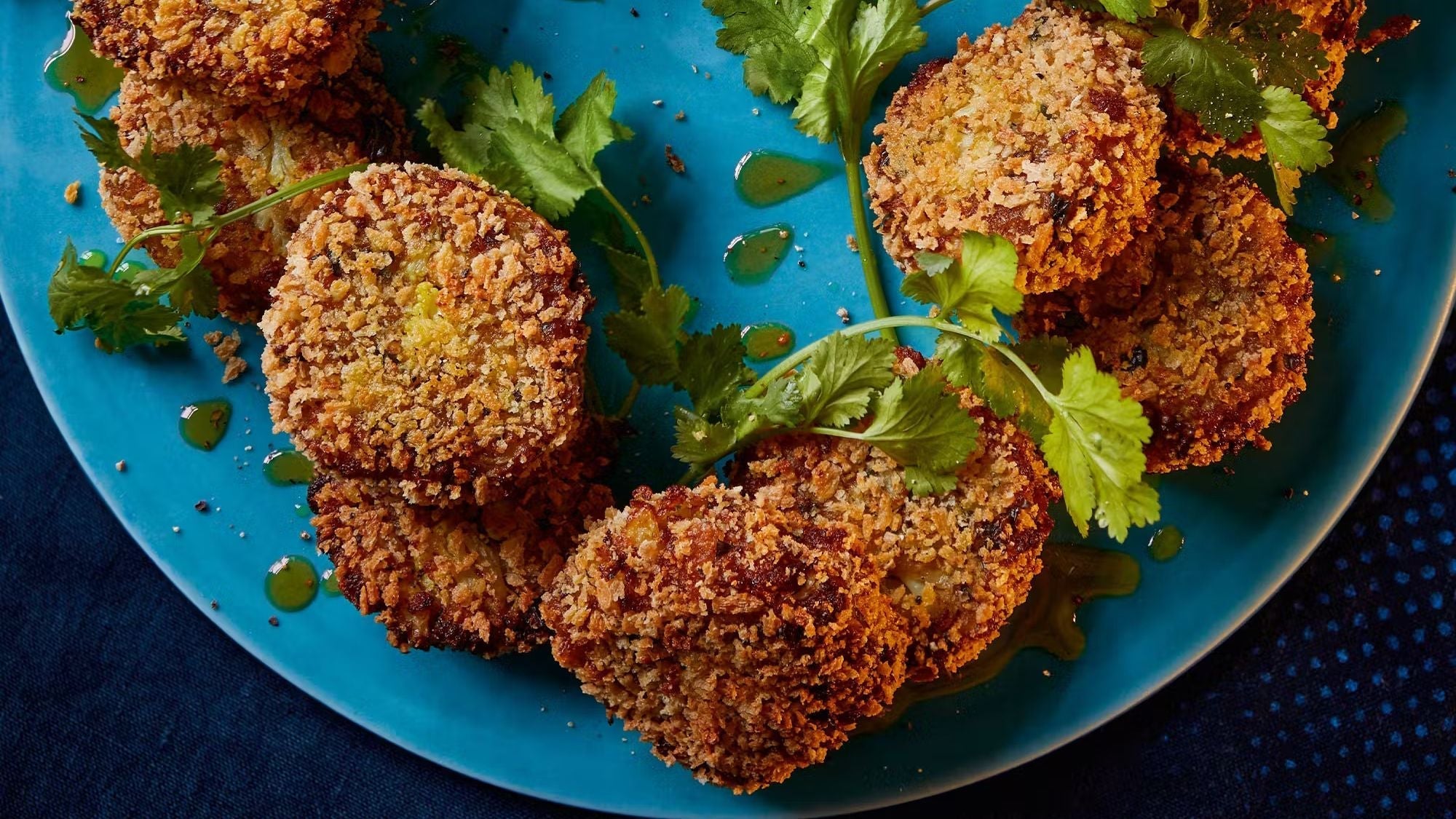 Crispy aloo gobi cutlets served on a blue plate, garnished with fresh coriander leaves