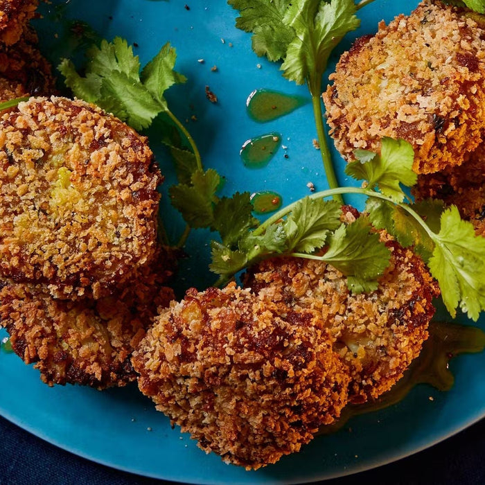 Crispy aloo gobi cutlets served on a blue plate, garnished with fresh coriander leaves