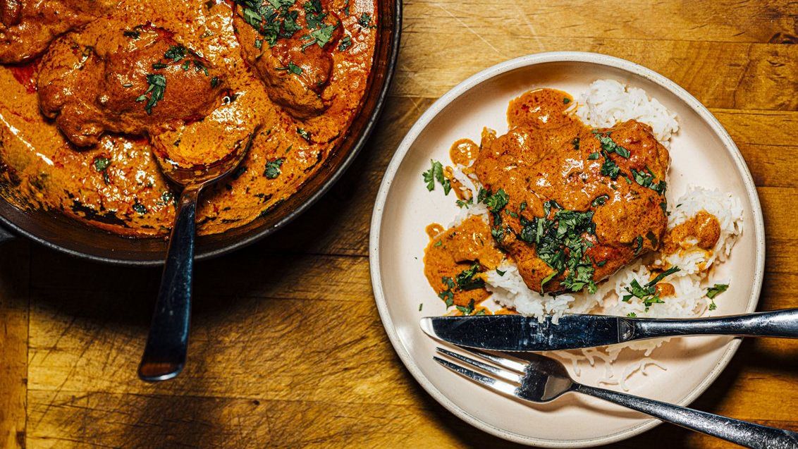 Butter chicken curry served with steamed rice, garnished with fresh herbs on a plate