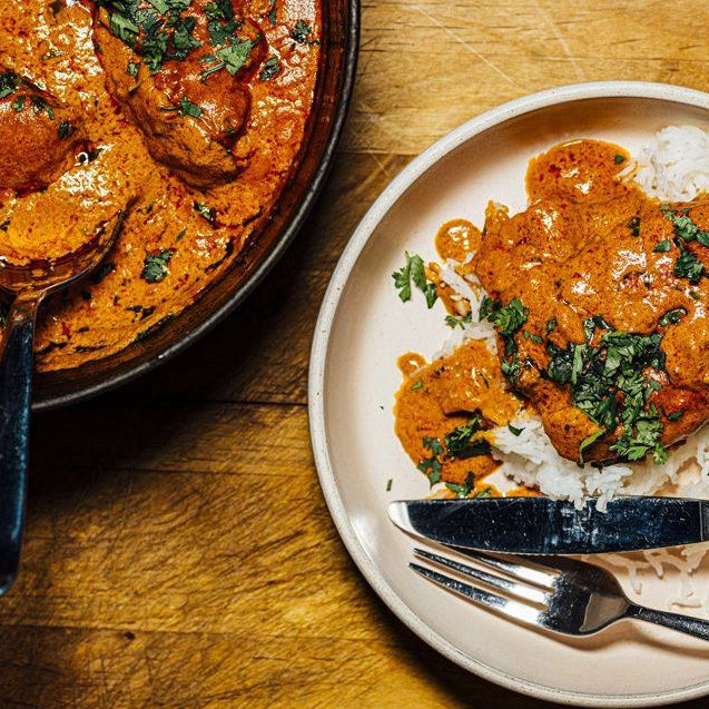 Butter chicken curry served with steamed rice, garnished with fresh herbs on a plate