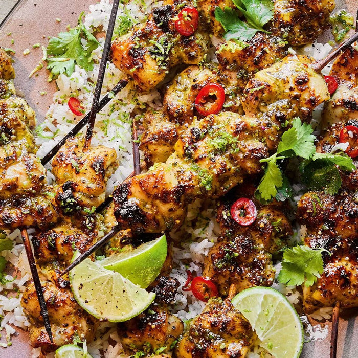 Charred Thai green curry chicken skewers piled on top of fluffy coconut jasmine rice, served with a fresh cucumber and sugar snap pea salad.