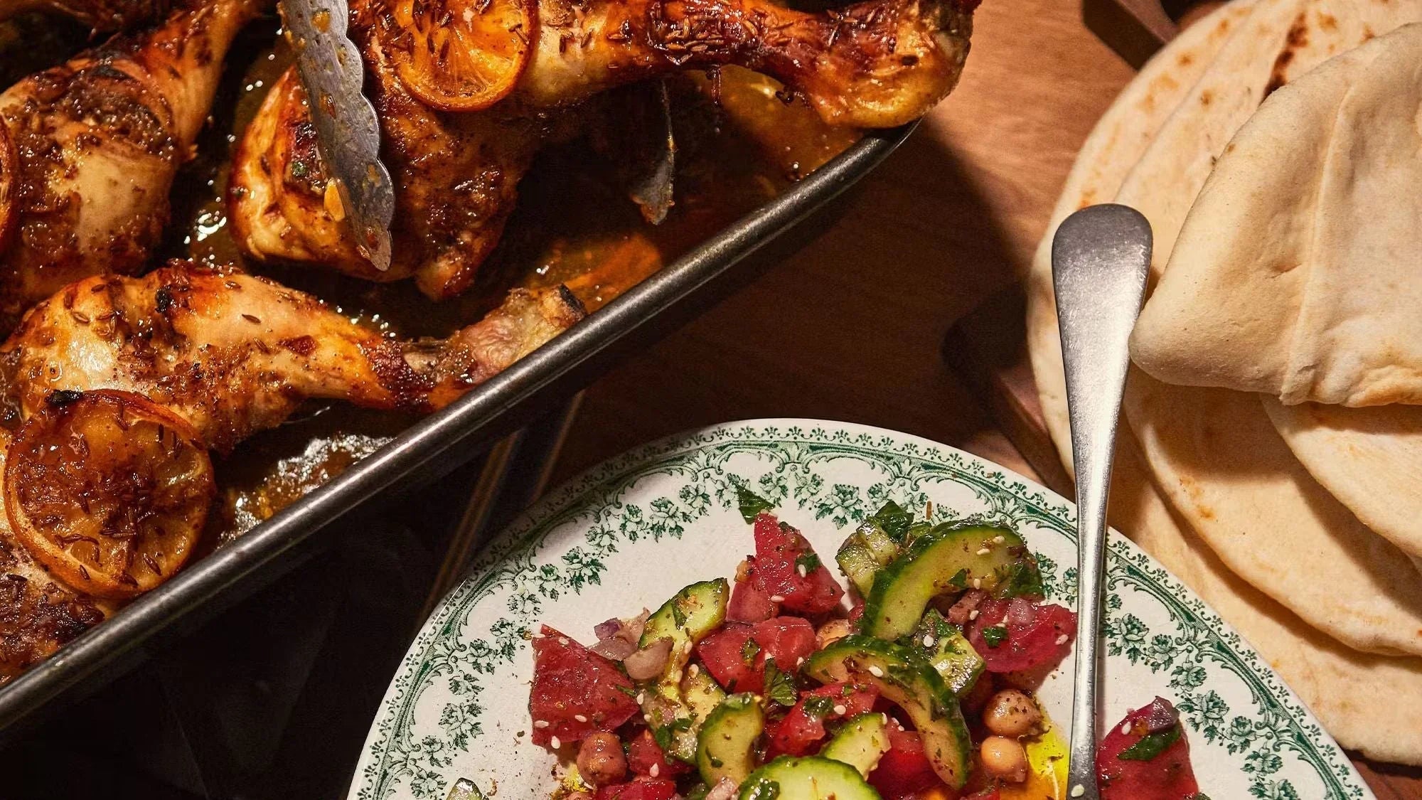Roast cumin and lemon chicken with Persian salad, pita bread, and vintage plate on table
