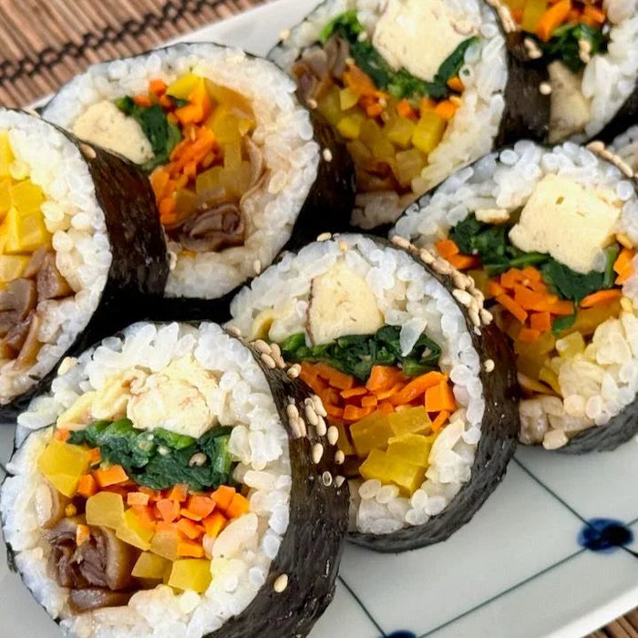 Korean gimbap rice rolls with seaweed, vegetables, and tofu on a white plate