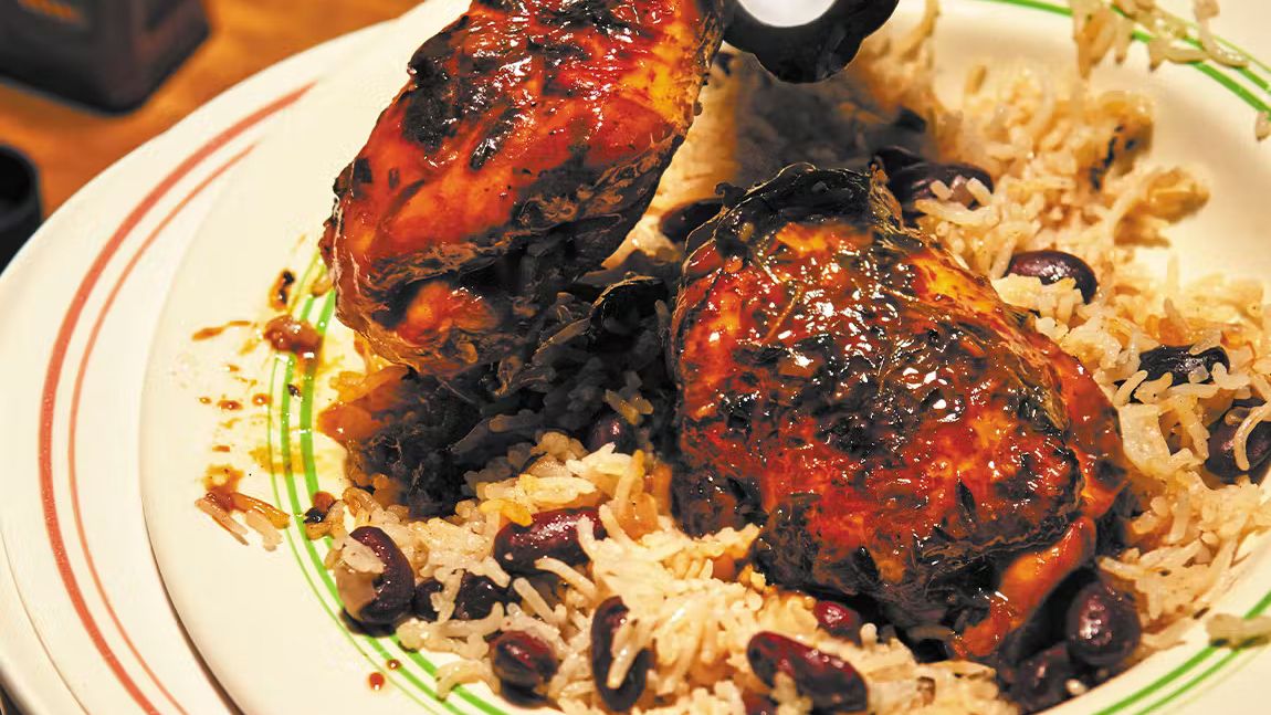 Plate of stewed chicken with herbs served over rice and peas, Caribbean comfort food