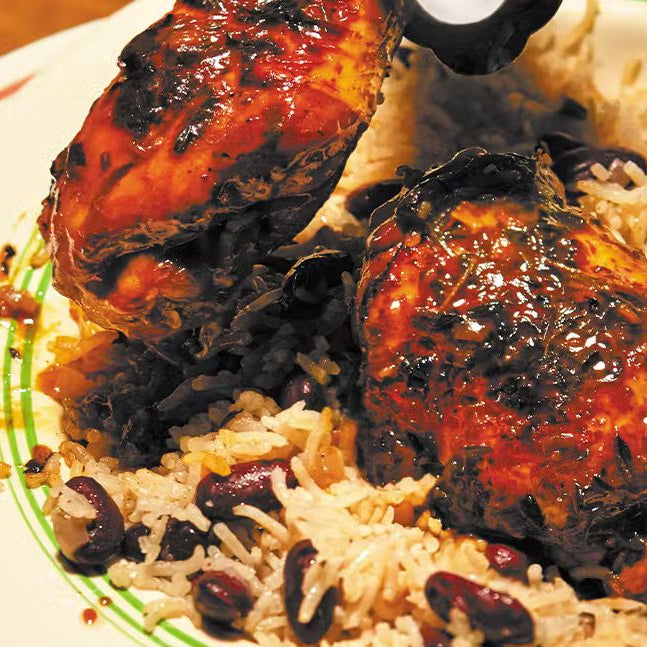 Plate of stewed chicken with herbs served over rice and peas, Caribbean comfort food