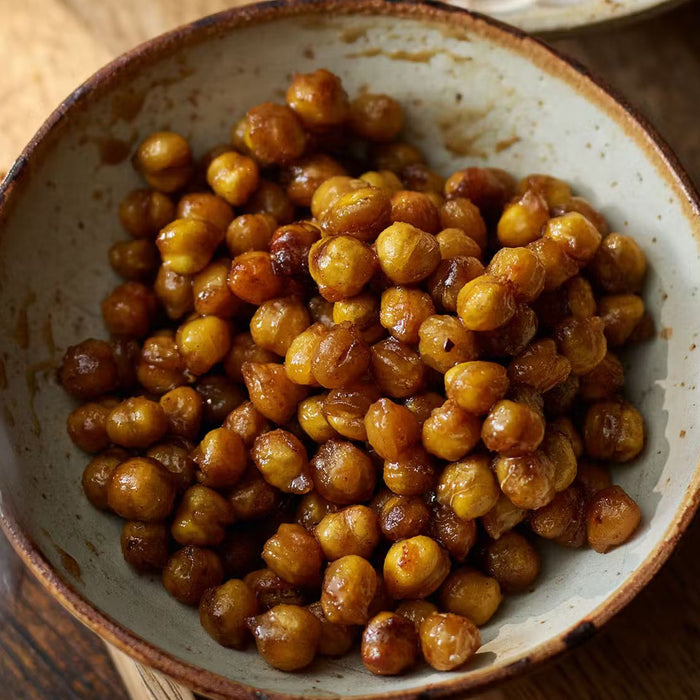 Bowl of roasted maple and cinnamon chickpeas on rustic wooden table