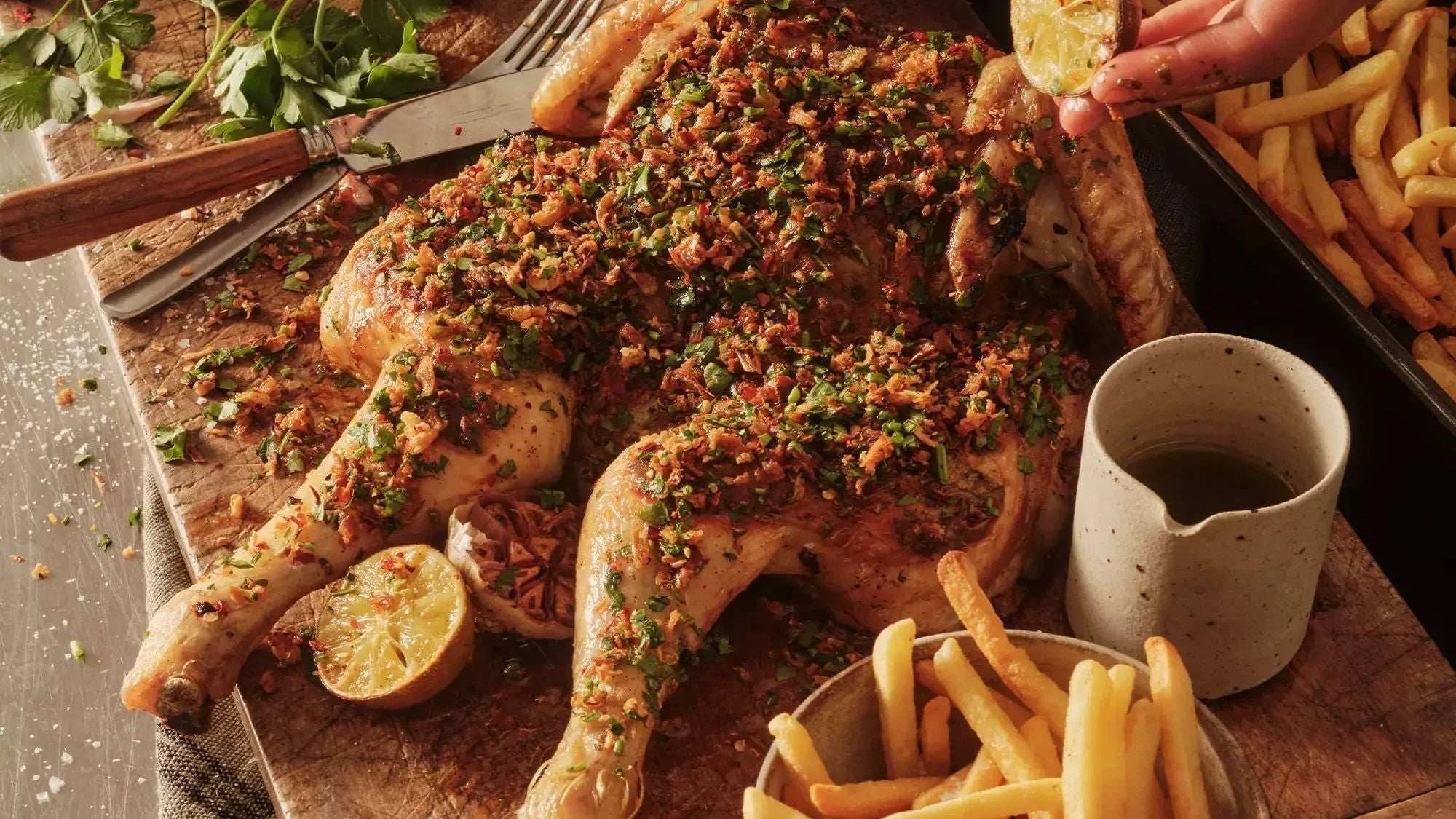 Herb butter roasted spatchcock chicken garnished with fresh parsley and served with fries
