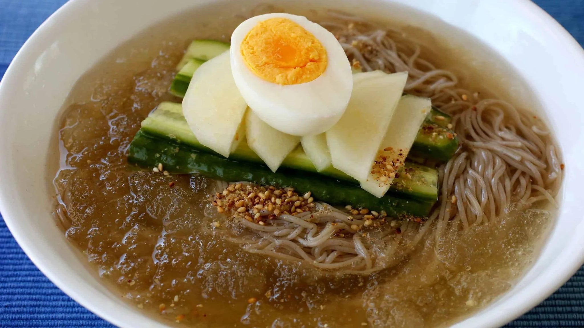 Mul naengmyeon cold Korean noodles in broth with egg, cucumber, pear and sesame seeds