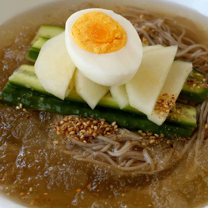 Mul naengmyeon cold Korean noodles in broth with egg, cucumber, pear and sesame seeds