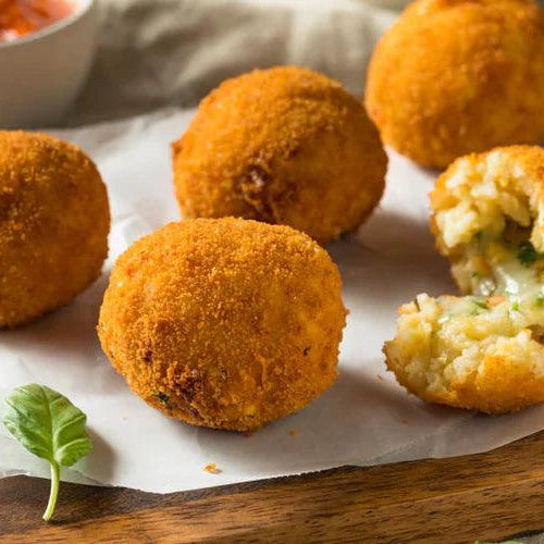 Golden oak-smoked paprika and tomato pesto croquettes on parchment with dipping sauce