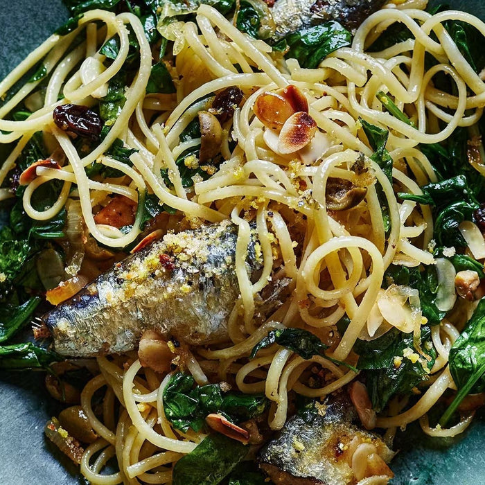 Linguine pasta with sardines, spinach, olives, and crunchy toasted crumbs in a bowl