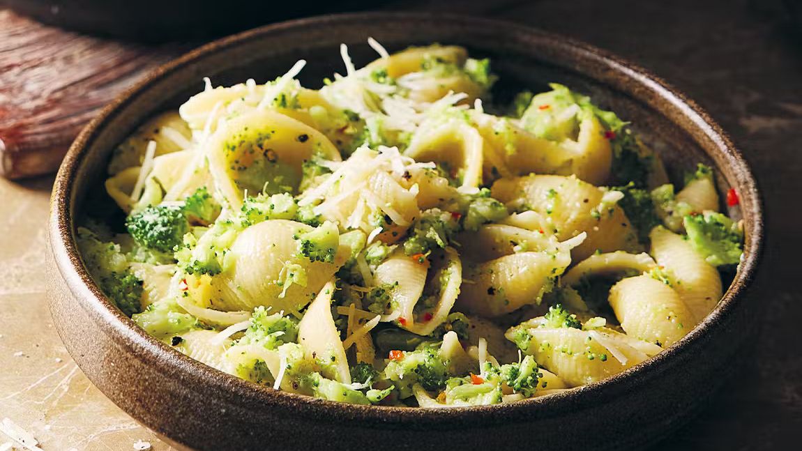 Shell pasta with broccoli and grated cheese in a rustic ceramic bowl, Italian vegetarian dinner.