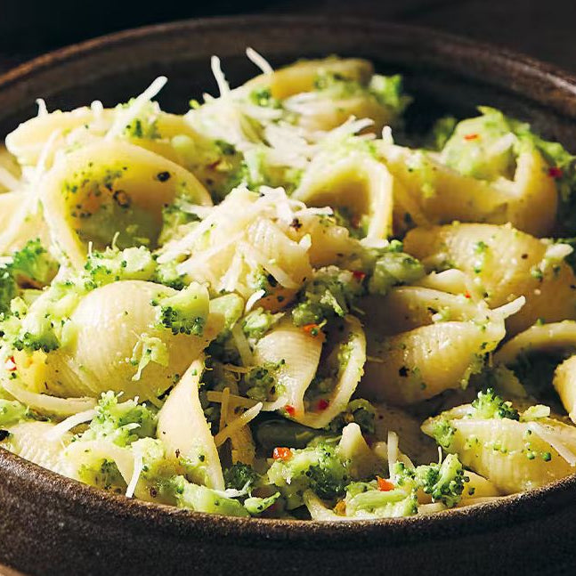 Shell pasta with broccoli and grated cheese in a rustic ceramic bowl, Italian vegetarian dinner.