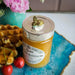 Honey jar with decorative bee lid on a blue tray, next to waffles and cherries